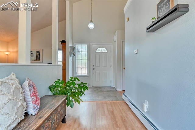 foyer entrance featuring a baseboard radiator, high vaulted ceiling, wood finished floors, and baseboards