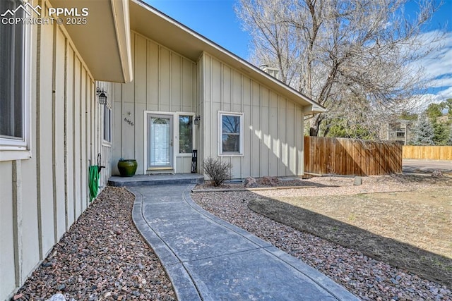 property entrance featuring board and batten siding and fence