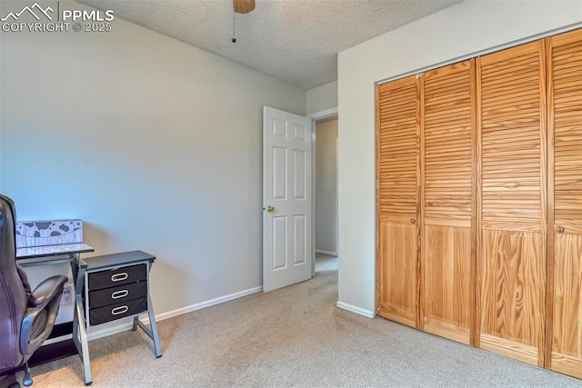 carpeted office featuring baseboards, ceiling fan, and a textured ceiling
