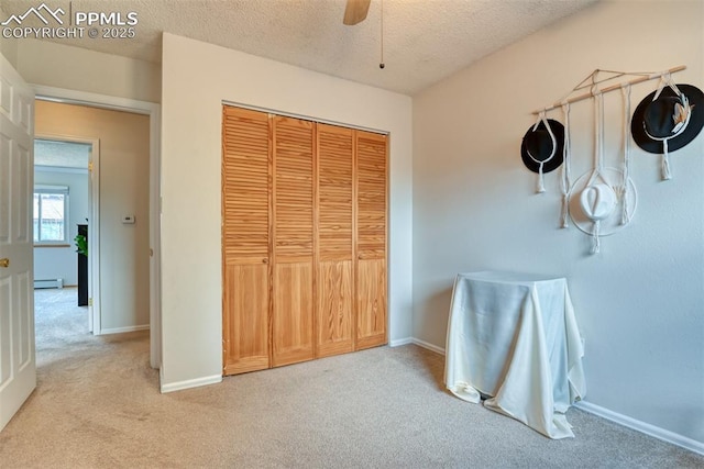 bedroom with light carpet, baseboards, a baseboard heating unit, and a textured ceiling
