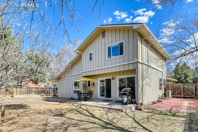 rear view of house with a fenced backyard, board and batten siding, a lawn, and a patio area