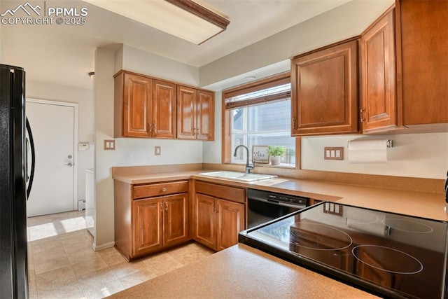 kitchen with brown cabinets, black appliances, light countertops, and a sink