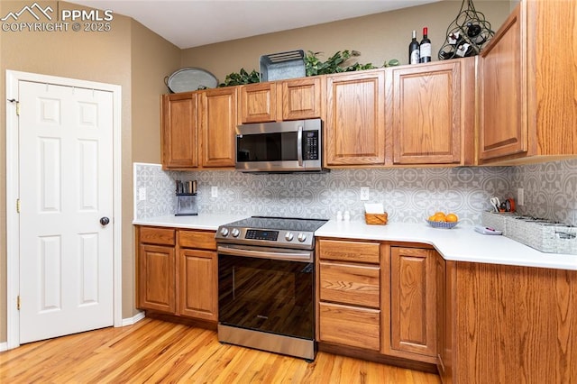 kitchen with light countertops, light wood-style flooring, brown cabinetry, and stainless steel appliances