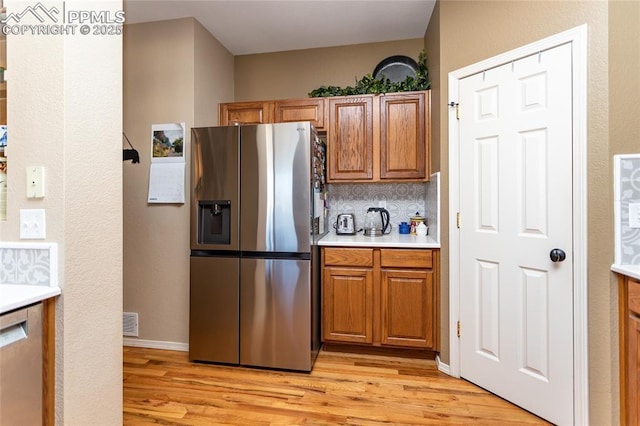 kitchen with brown cabinets, stainless steel appliances, light countertops, and light wood-style floors