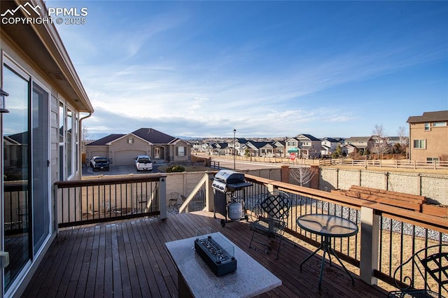 wooden terrace featuring a fire pit, a residential view, and grilling area