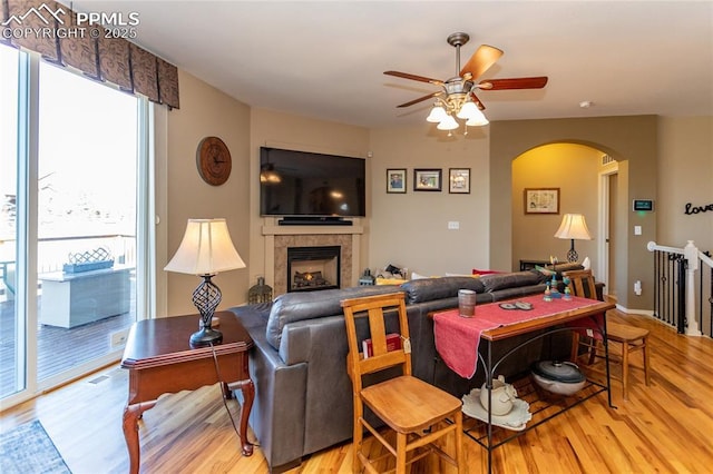 living area featuring visible vents, a ceiling fan, wood finished floors, arched walkways, and a fireplace