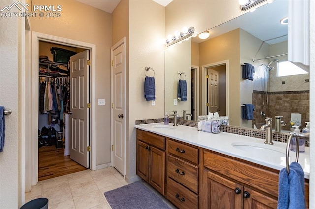 bathroom with tiled shower, double vanity, a sink, tile patterned flooring, and a walk in closet