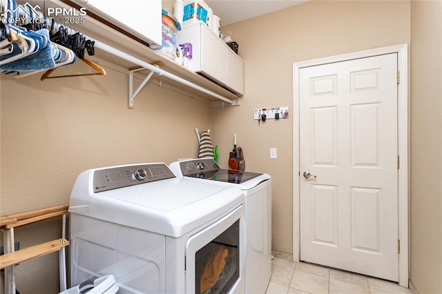 washroom with light tile patterned floors, cabinet space, and washer and clothes dryer