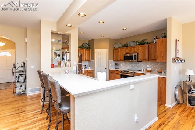 kitchen with light wood-style flooring, visible vents, appliances with stainless steel finishes, and brown cabinets