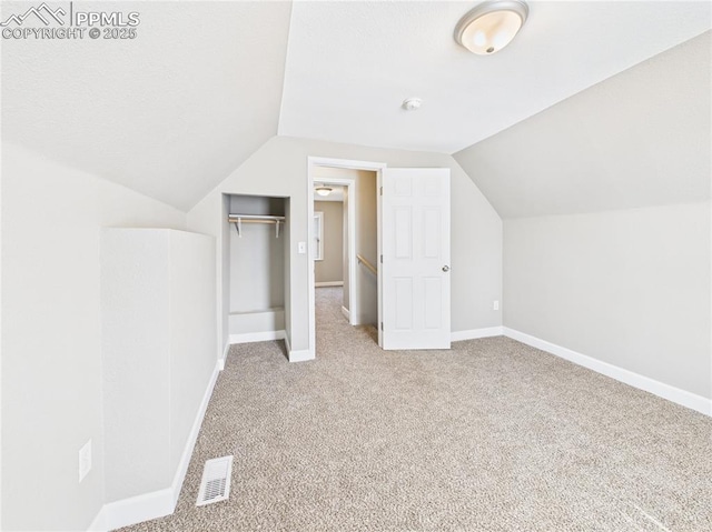 additional living space with baseboards, visible vents, carpet floors, and lofted ceiling
