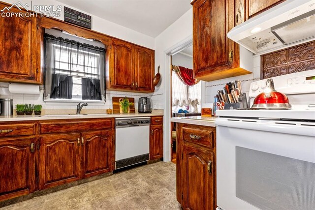 kitchen with extractor fan, light countertops, decorative backsplash, white appliances, and a sink