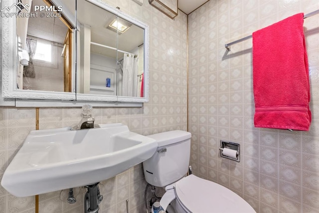 bathroom with wallpapered walls, toilet, and a sink