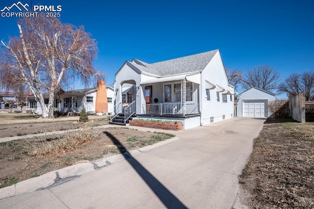 bungalow with an outbuilding, a detached garage, covered porch, concrete driveway, and a shingled roof