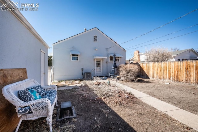 rear view of property with central air condition unit, fence, and stucco siding