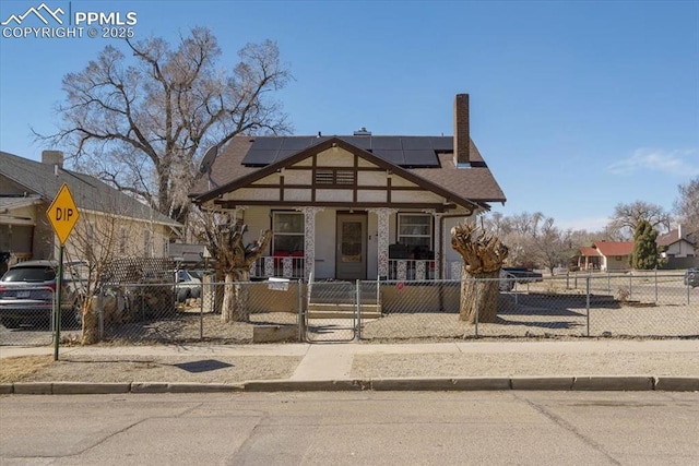 view of front of property with solar panels, a fenced front yard, a porch, a chimney, and a gate