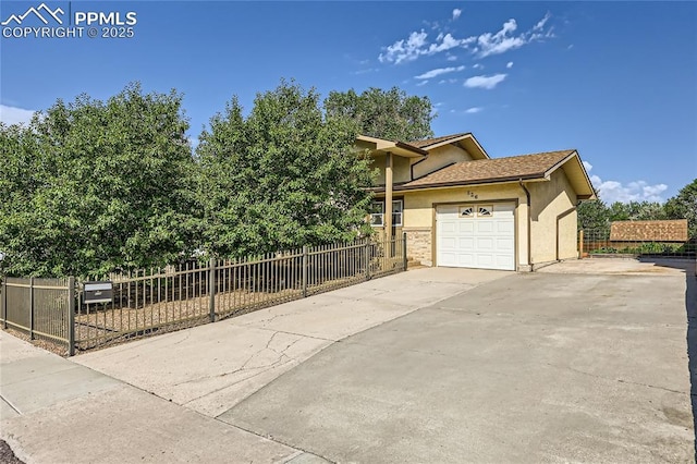 view of side of property with stucco siding, driveway, an attached garage, and fence