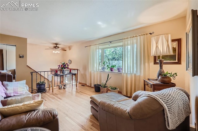 living room with baseboards, light wood-type flooring, and a ceiling fan