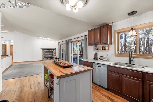 kitchen featuring lofted ceiling, a sink, dishwasher, light wood-type flooring, and butcher block counters