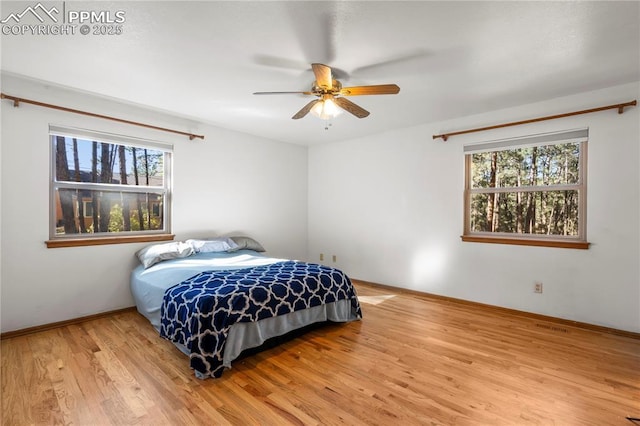 bedroom with light wood finished floors, visible vents, baseboards, and a ceiling fan