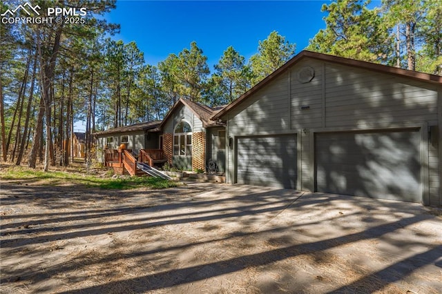 view of front of house with a garage, brick siding, and dirt driveway