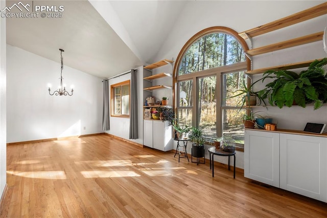 interior space with a notable chandelier, baseboards, light wood finished floors, and high vaulted ceiling