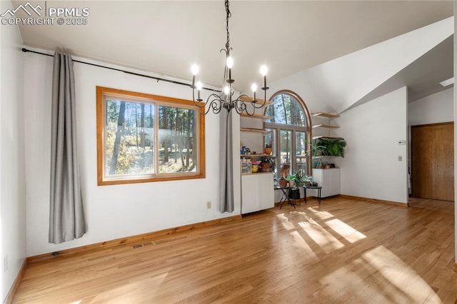 unfurnished dining area with an inviting chandelier, lofted ceiling, wood finished floors, and baseboards