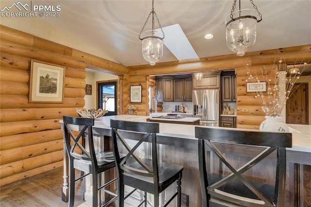 kitchen with a breakfast bar, wood finished floors, stainless steel fridge, light countertops, and vaulted ceiling