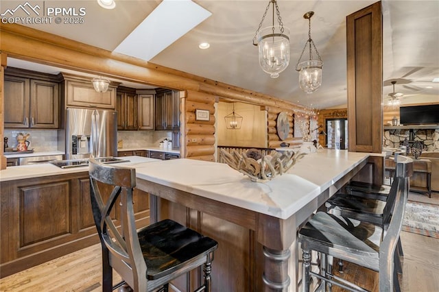 kitchen featuring rustic walls, a breakfast bar area, stainless steel refrigerator with ice dispenser, and light countertops