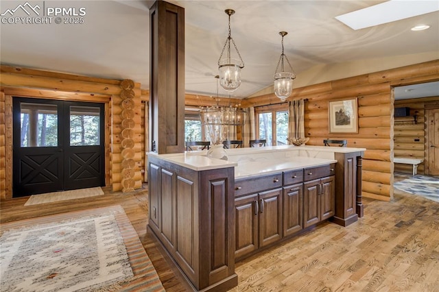 kitchen with light wood-type flooring, decorative light fixtures, light countertops, lofted ceiling, and dark brown cabinets