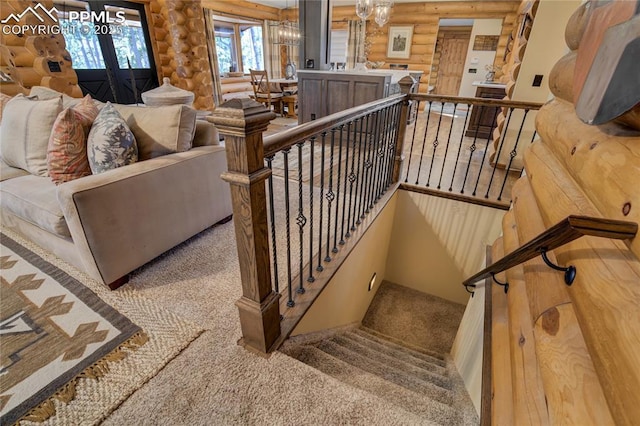 staircase with a chandelier and carpet flooring