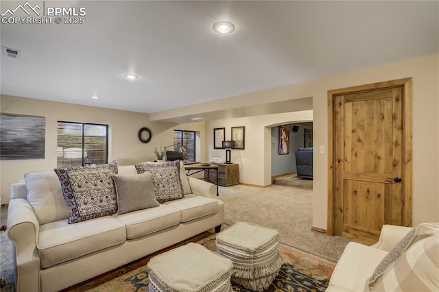 living room with visible vents, recessed lighting, arched walkways, baseboards, and light colored carpet