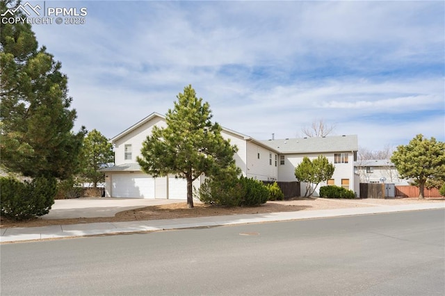 view of front of home featuring driveway, a garage, and fence