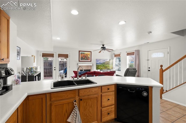 kitchen with a peninsula, a fireplace, a sink, black dishwasher, and open floor plan