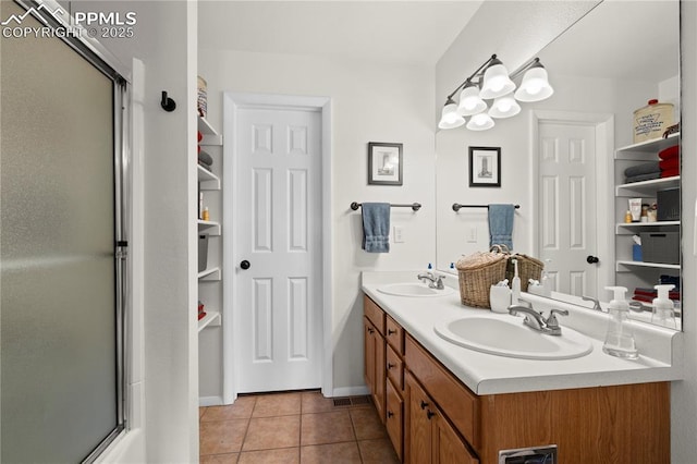 bathroom featuring tile patterned floors, a shower with shower door, and a sink