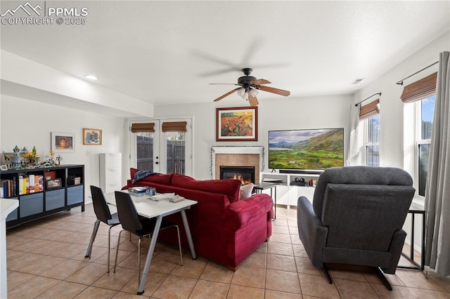 living room featuring visible vents, a ceiling fan, french doors, a fireplace, and light tile patterned floors