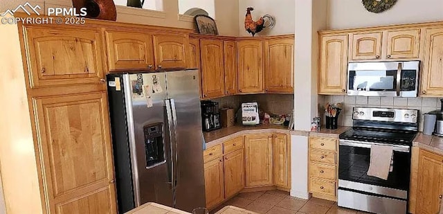 kitchen with light countertops, backsplash, light tile patterned flooring, and appliances with stainless steel finishes