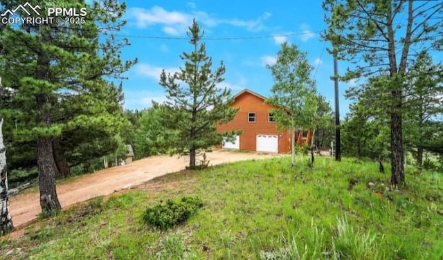 view of yard with a garage and driveway