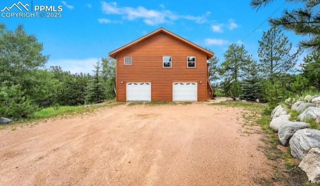 view of home's exterior featuring a garage and dirt driveway