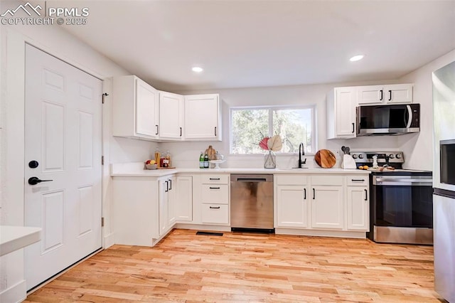 kitchen featuring light wood-style flooring, white cabinetry, stainless steel appliances, and light countertops