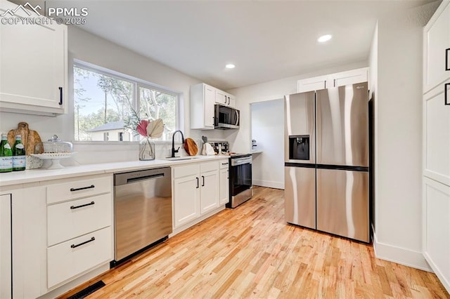 kitchen with white cabinetry, light wood finished floors, appliances with stainless steel finishes, and a sink