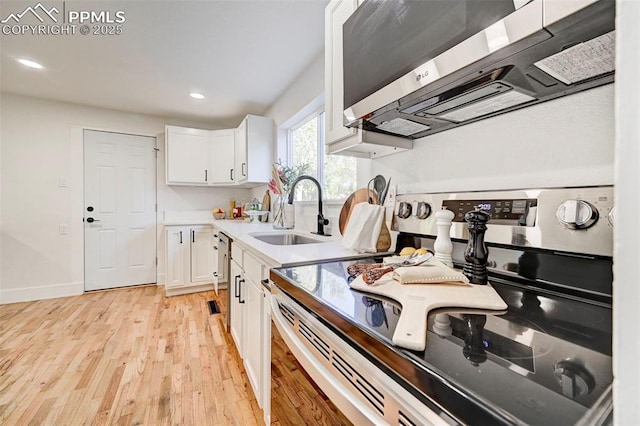 kitchen featuring recessed lighting, a sink, stainless steel appliances, white cabinetry, and light wood-type flooring