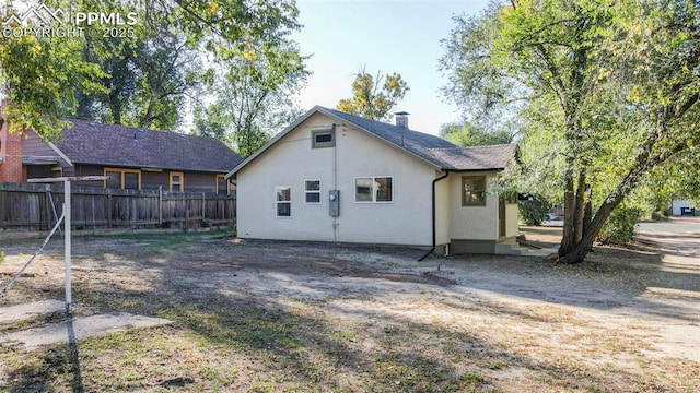 back of house featuring fence and stucco siding