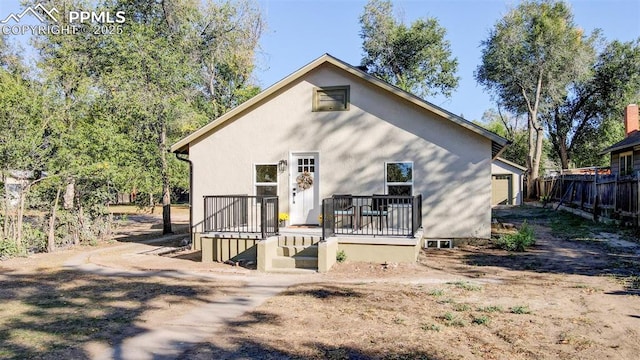 rear view of house with a wooden deck, a garage, and fence