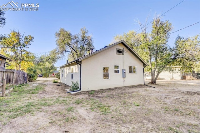 rear view of property with stucco siding and fence