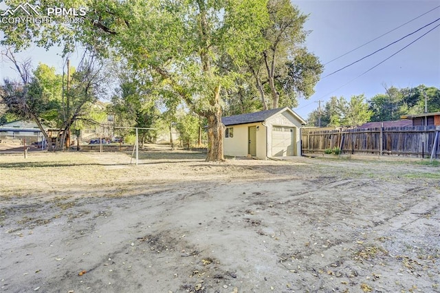 view of yard with an outdoor structure, fence, and a detached garage