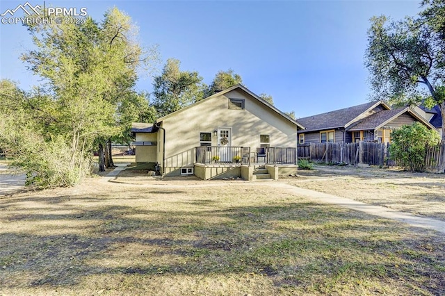 back of property with fence and a wooden deck