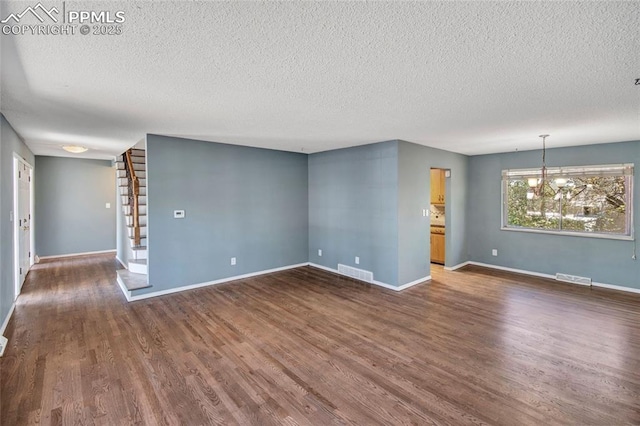 empty room with dark wood-style flooring, a textured ceiling, and visible vents