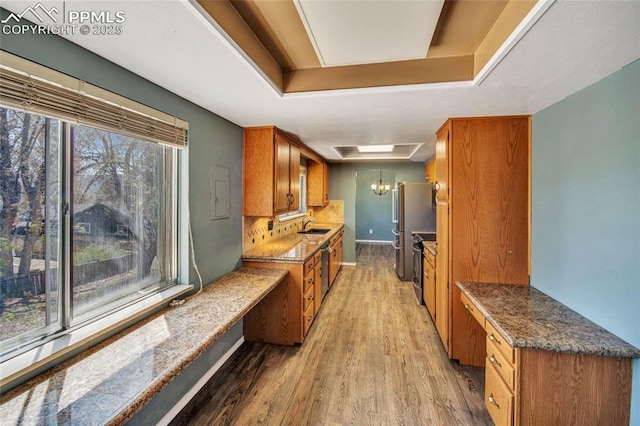 kitchen featuring brown cabinetry, light wood-style floors, a sink, and baseboards