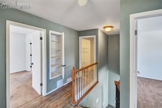 hall with carpet floors, baseboards, and an upstairs landing