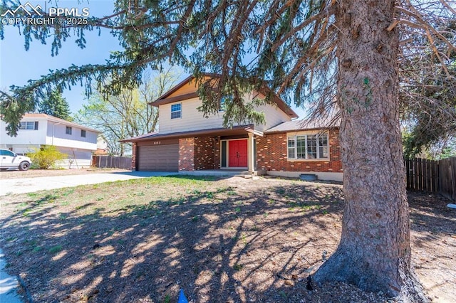 traditional-style house with fence, an attached garage, brick siding, and driveway